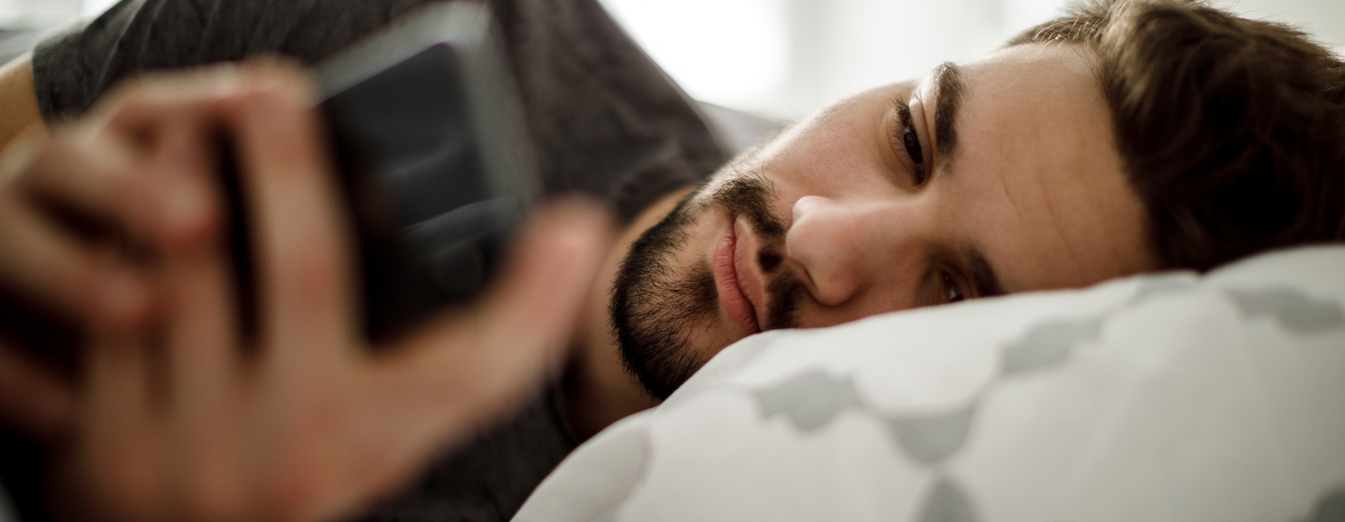 man laying in bed with phone